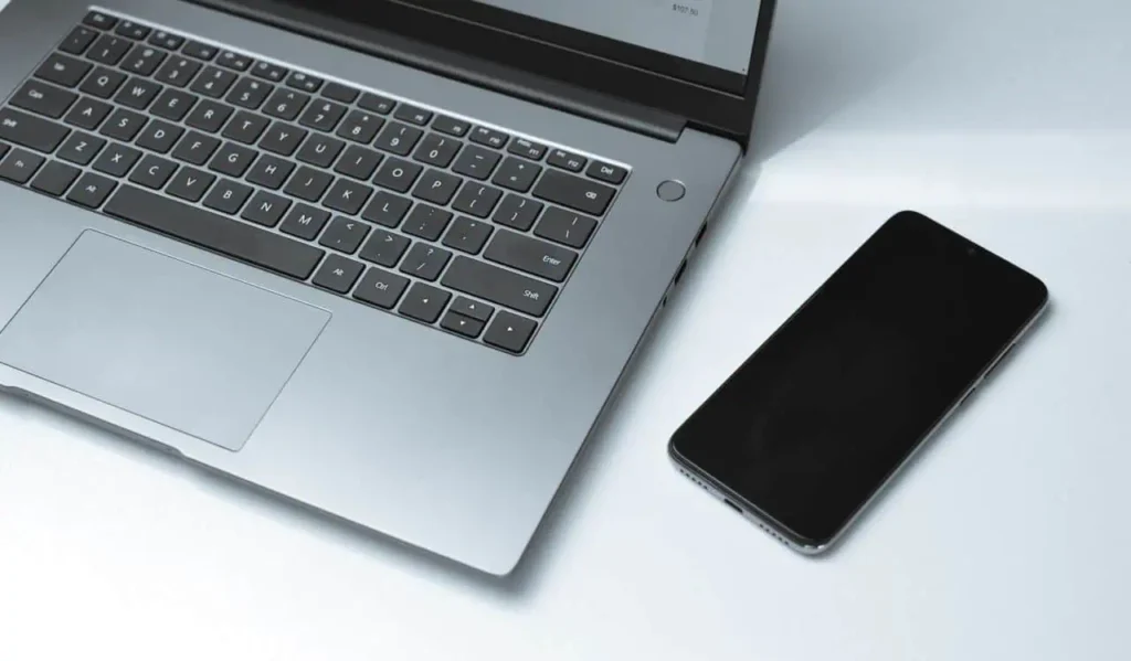 Laptop computer and smartphone placed together on clean white surface