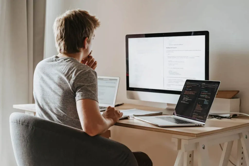 Software developer working at desktop computer and laptop workstation